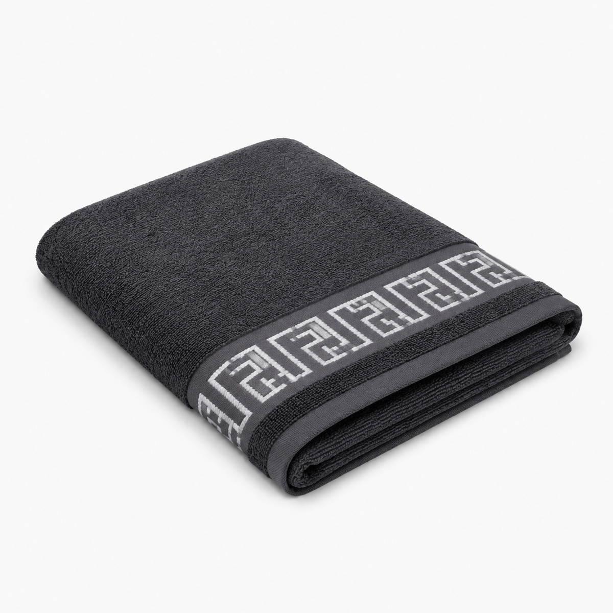 Serviette de bain en coton à motif méandre pliée à côté d'une plante et d'un savon artisanal